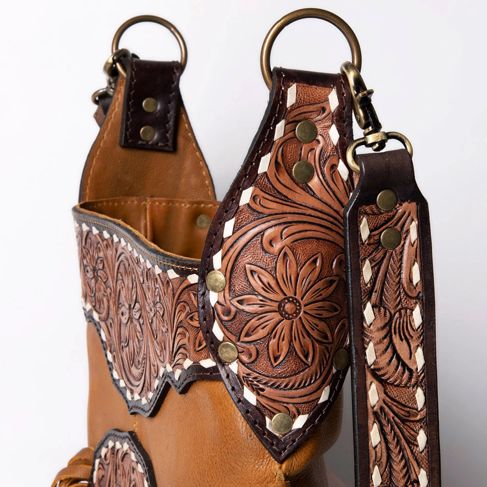 Close-up of a brown leather boot with intricate floral tooled design on a white background
