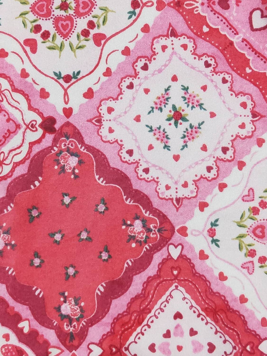 Patterned fabric with red, pink, and white colors featuring floral and heart designs.